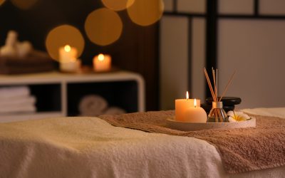 Burning candles and aromatic reed freshener on table in spa salon, space for text